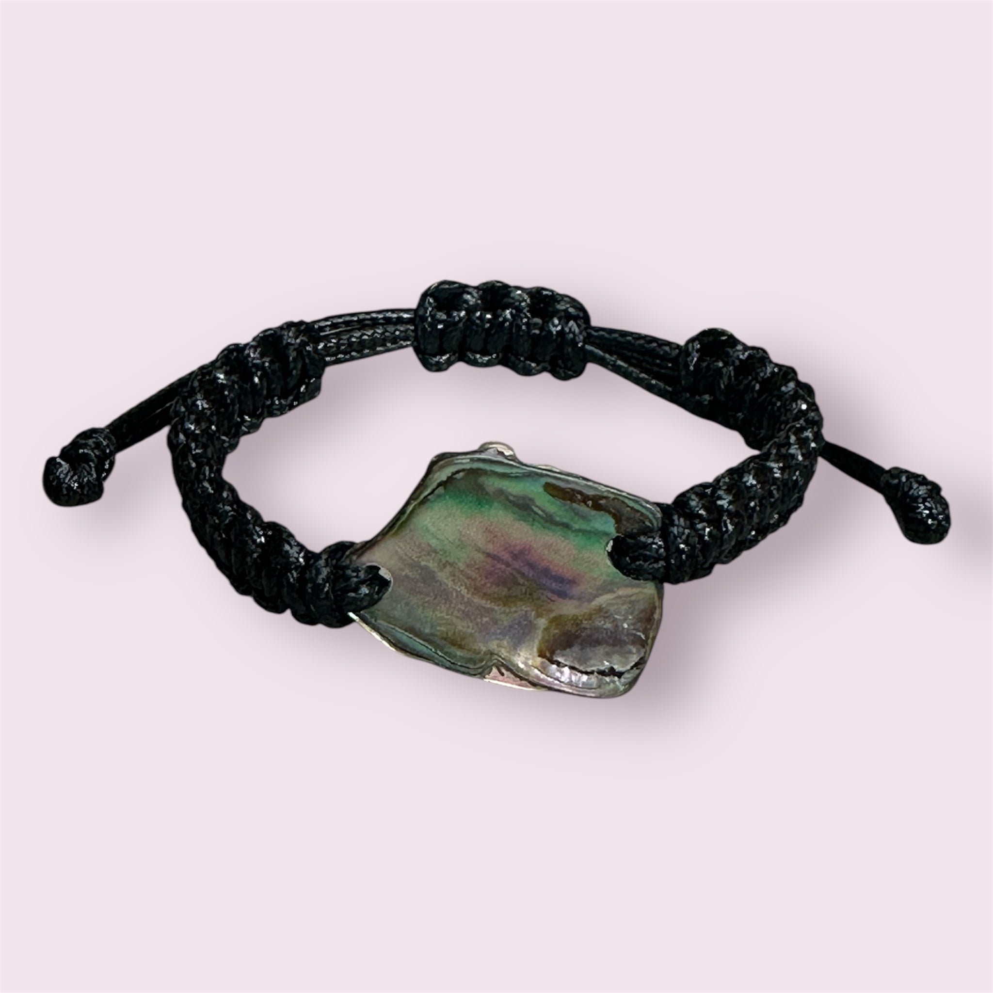 Close view of Paua shell bracelet with adjustable black cord and unique shell patterns.