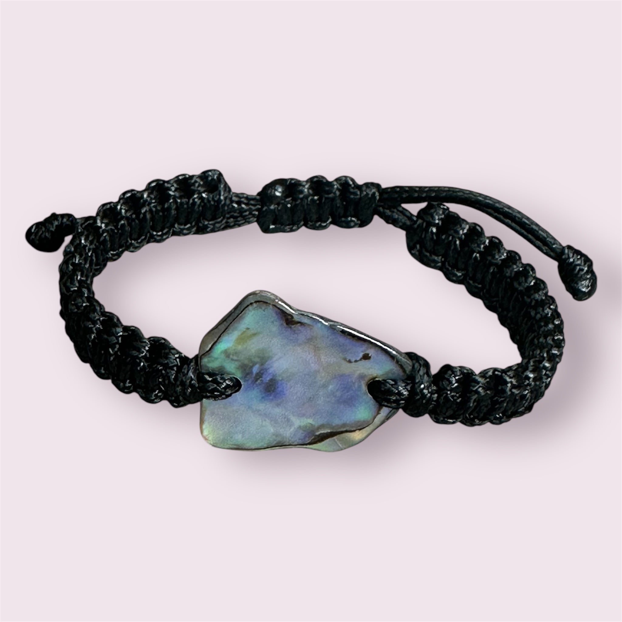 Black knotted bracelet styled on wrist, showing the shine and colour of the Paua shell.