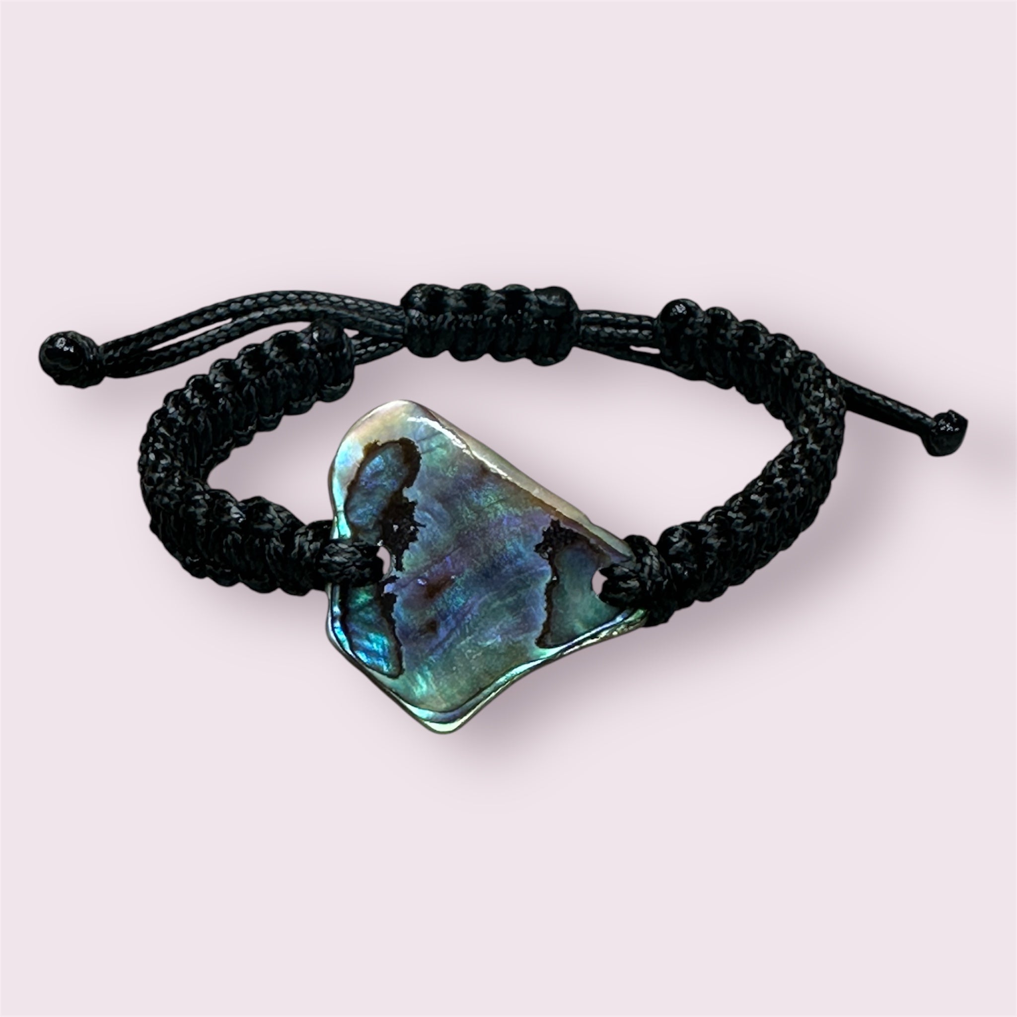 Handmade square knot bracelet with a central Paua shell, shown in natural light.
